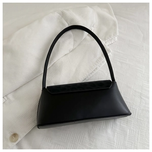 Detail of a black faux leather baguette bag on white textured corduroy fabric