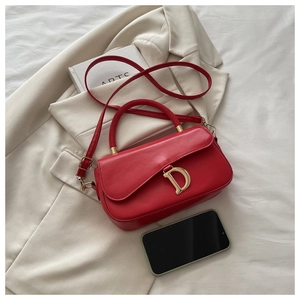 Vue détaillée d'un sac à main rouge avec un pendentif en métal doré en forme de D