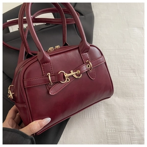 Close-up of retro burgundy handbag featuring matte PU leather and gold metal buckle detail