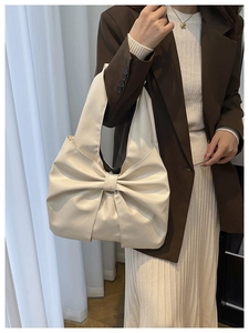 Détail d'un sac à bandoulière crème avec un grand nœud et des plis doux style sac hobo