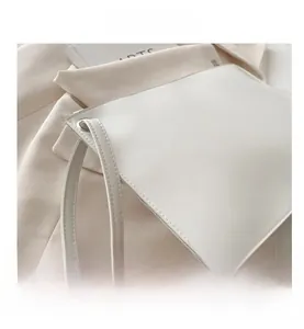 Macro shot of white minimalist PU leather tote bag details with wristlet and metal buckle