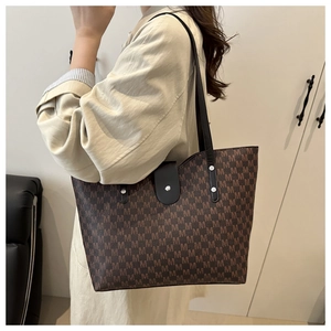 Brown monogram tote bag with leather strap and metal buckle shown on shoulder