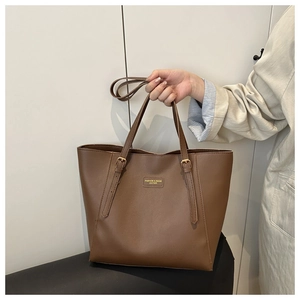 Détail de la boucle métallique réglable sur le sac cabas en cuir marron avec marquage or