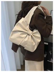 Détail d'un sac à bandoulière en cuir blanc crème avec un grand nœud et texture plissée