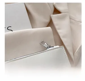 Close-up of smooth silver metal zipper on white leather handbag with clean stitching details
