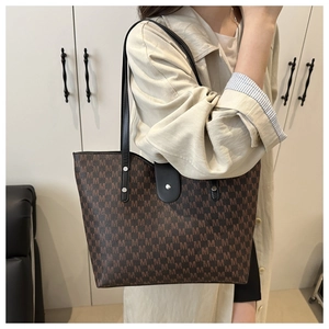 Close-up of large tote bag featuring brown M-letter print and black shoulder straps