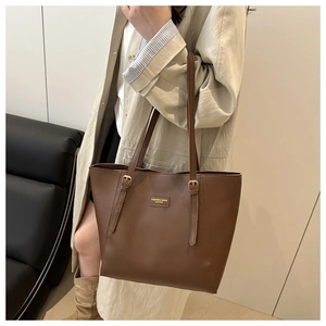 Détail d'un cabas en cuir marron avec logo doré et bandoulières réglables élégantes