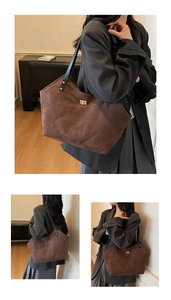 Gros plan d'un sac cabas en daim marron avec surpiqûres matelassées et fermoir doré