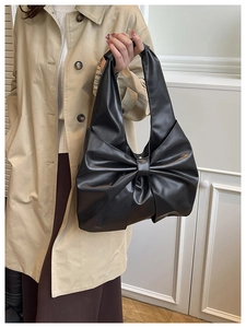 Détail du sac à bandoulière noir en PU avec grand nœud décoratif et texture plissée