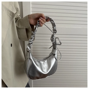 Detail of silver crescent bag with scrunchie strap and knot detail on trench coat