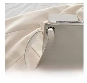 Macro detail of creamy white leather envelope bag with silver hardware and soft handle