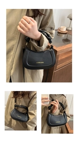 Detail view of black crescent handbag featuring knotted handle and gold zipper hardware
