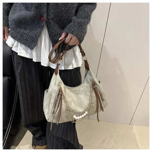 Close-up of silver-gray distressed tote with brown leather straps and pearl chain detail