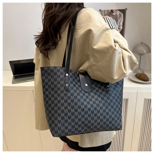 Close-up of large black tote bag with gray M-letter print and silver rivet details