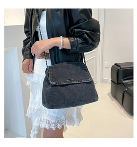 Detail of dark gray denim chain bag styled with a leather jacket and lace skirt