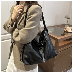 Detail of a large black chain tote bag paired with a khaki blazer for a modern work look