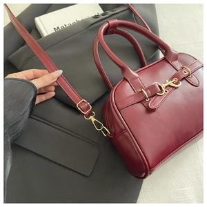 Close-up of burgundy leather shell bag with gold horsebit buckle and slim shoulder strap