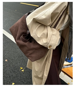 Outdoor street shot of a large dark brown suede tote bag worn with a beige trench coat