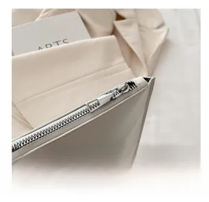 Close-up of sleek silver zipper on a creamy white minimalist faux leather handbag