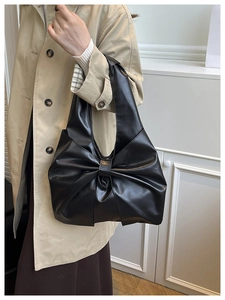 Détail d'un sac à main noir en forme de nœud avec des plis élégants et un design de ruban