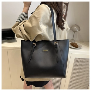 Détail du sac cabas en cuir noir avec boucle métallique dorée et étiquette de marque