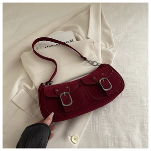 Macro detail of wine red underarm bag featuring dual front pockets and metallic buckles