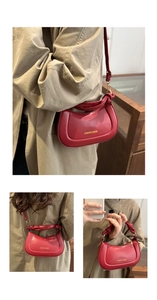 Detail of red crescent leather bag with knotted strap and gold fashion branding