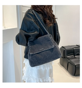 Detail of dark grey washed denim tote bag featuring silver chain strap and metal trim