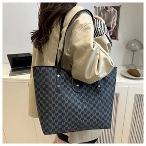 Close-up of large tote bag with M-letter pattern and black shoulder straps in lifestyle setting