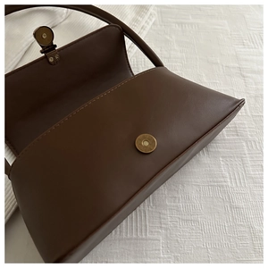 Detailed top view of dark brown leather shoulder bag featuring a vintage magnetic clasp