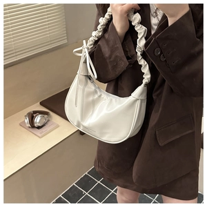 Detail of off-white hobo bag showing pleated shoulder strap and side bow detail