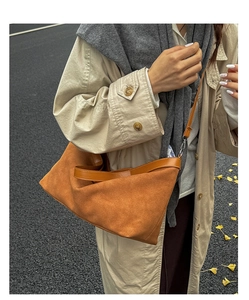 Detailed texture of brown suede tote bag with leather piping on street background
