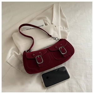 Detail of burgundy suede shoulder bag with twin buckled pockets and silver hardware