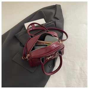 Detail view of burgundy leather Boston bag showing spacious interior on grey suit