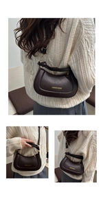 Detail view of a brown half-moon shoulder bag with gold hardware and fashion lettering