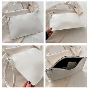Detail view of minimalist white tote bag with metal zipper, wrist strap, and black lining