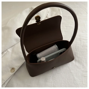 Detailed interior of the brown matte handbag showing gold magnetic clasp and storage capacity