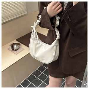 Detail of white pleated shoulder bag with scrunched handle and glossy finish on leather