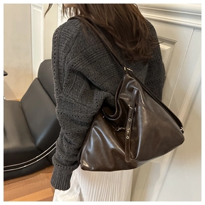 Detail of wide shoulder strap and matte brown leather texture on oversized tote bag
