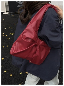 Vue détaillée d'un grand sac à bandoulière rouge avec un design de nœud plissé chic