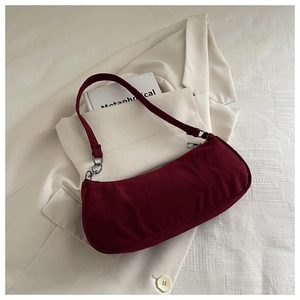 Detail of burgundy baguette underarm bag with silver ring hardware and zipper closure