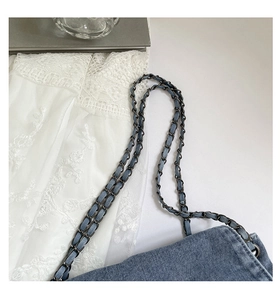 Close-up of blue denim tote bag with black metal chain strap and woven fabric detail
