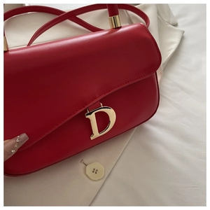 Détail du sac à main en cuir rouge luxe avec boucle en D dorée et finitions métalliques