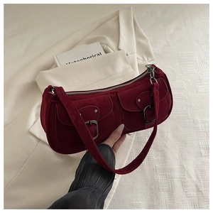 Detail view of burgundy suede shoulder bag with twin front buckle pockets and metal studs