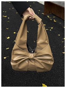 Détail du sac à main kaki avec un grand nœud élégant et une texture en cuir mat