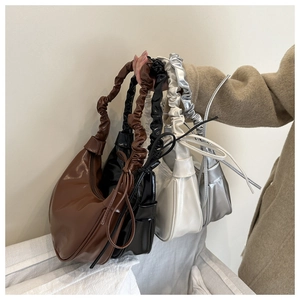 Close-up of four glossy faux leather crescent hobo bags with ruffled strap and side tassels