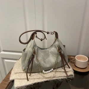 Sage green canvas tote bag with brown leather trim and pearl chain on a scarf