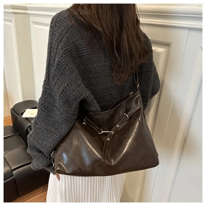Detail of dark brown leather tote bag showing glossy texture and metal eyelet straps
