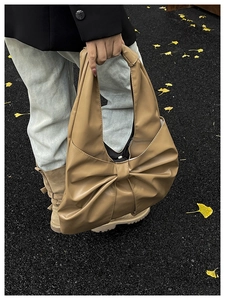 Détail du sac à bandoulière en PU kaki avec grand nœud dans une scène de rue automnale