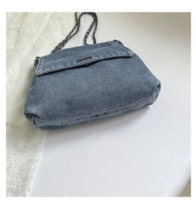 Detailed view of blue denim shoulder bag texture with dark metal chain strap accents